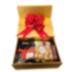Gold gift box with a red bow, holding a bottle and wrapped cookies with Italian labels on black filler, against a white background.