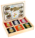 Wooden box displaying six colorful Ceylon tea packets, each from different regions. Map and illustrations on the lid enhance the exotic theme.