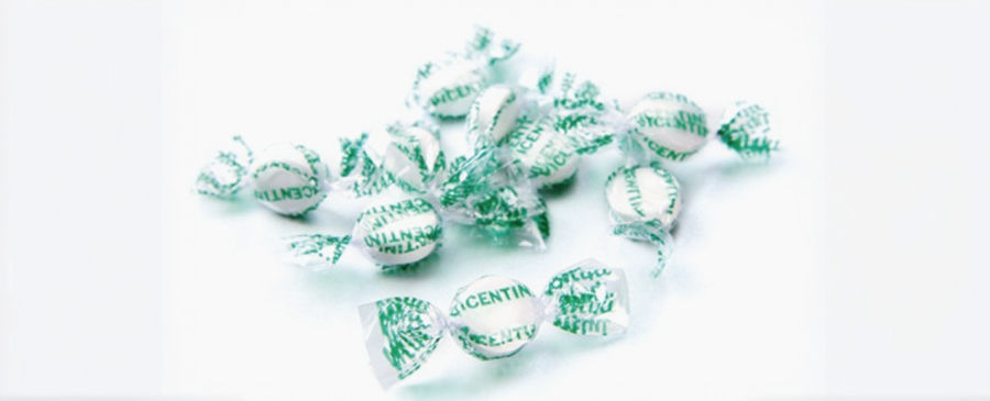Wrapped mint candies with green text on clear wrappers scattered on a white background. The text reads "VICENTIN."