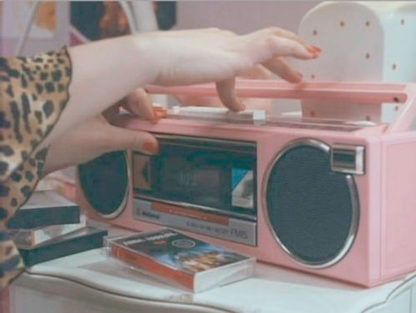 Woman hitting record on a boom box to record a song onto a mixtape