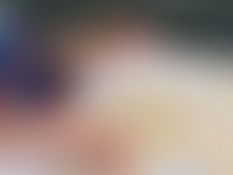 baby in a high chair wearing a bib, eating small pieces of orange.