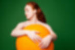 a young beautiful woman holding a very larger orange