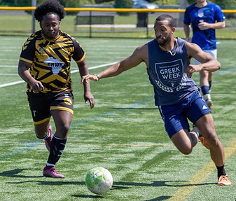 Two soccer players go after the ball on a soccer field
