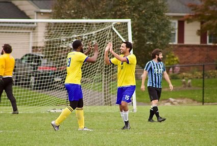 Soccer Players in yellow high five each other on the field