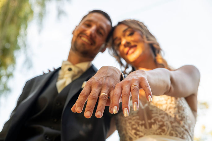 Photographie de mariage en Île-de-France, shooting couple au Vieux Moulin d'Us, les mariés mettent leur mains au premier plan et montrent leur alliances. 