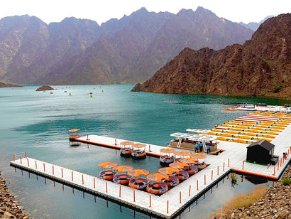 Hatta Kayak floating pontoon and turquoise reservoir surrounded by Hajar Mountains in the UAE desert