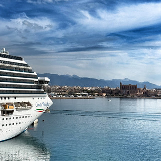 Ferry leaving port, city in background, clouds in sky