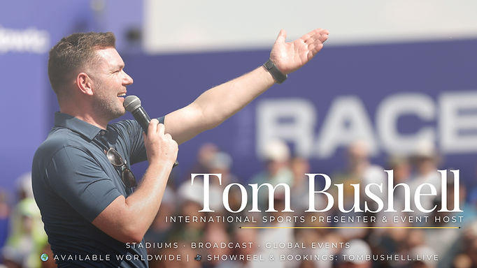 Tom Bushell media kit stands with arm raised talking into microphone to fans