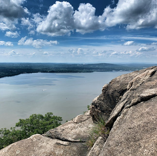 Rock ledge viewpoint on Breakneck Ridge overlooking the Hudson River under blue sky
