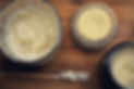 Large glass container of body butter along with two smaller tins