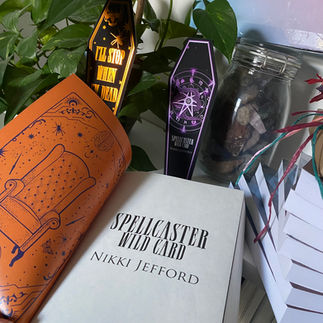 An open book titled Spellcaster Wild Card by Nikki Jeffod