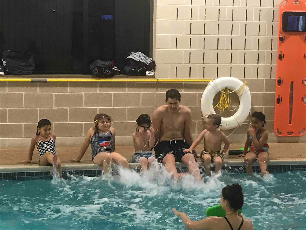 Swim School Coach James teaches his swimmers how to flutter kick in their swim lessons.