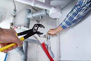 Young Plumber Working With Pipe Wrench In Kitchen.jpg