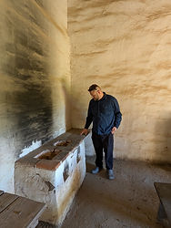 Man examining a wooden trough in an ancient chamber