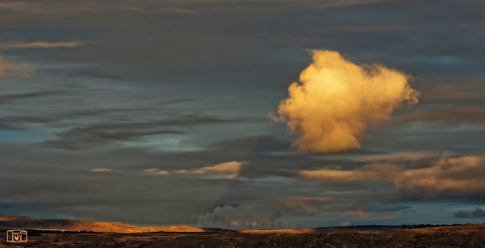 a puffy cloud casts a shadow on to surrounding clouds as the sun sets