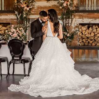 A bride and broom pose and stand close to one another.