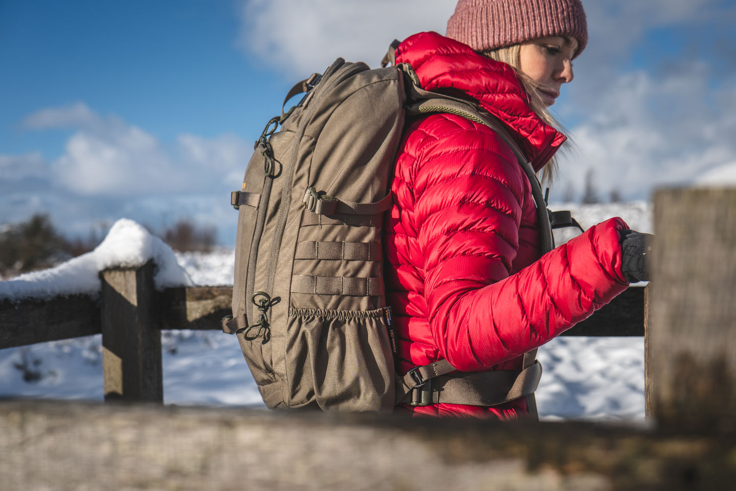 Frau in roter Jacke mit Rucksack auf winterlicher Wanderung