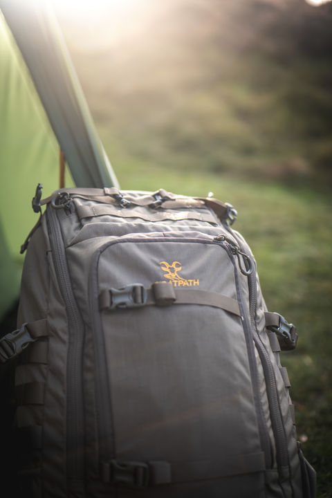 Grauer Rucksack mit Goatpath-Logo, vor einem Zelt