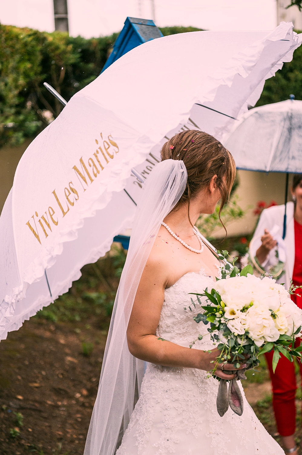 Mariée portant un parapluie blanc de mariage sous la pluie