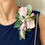 Thumbnail: Lady in blue dress with sparkles wearing dress corsage pinned onto shoulder with soft pink roses
