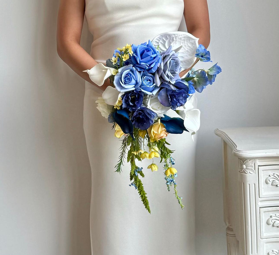 Woman in white dress holding asymmetrical bouquet with cornflower periwinkle blue real touch rose, yellow roses, bellflower