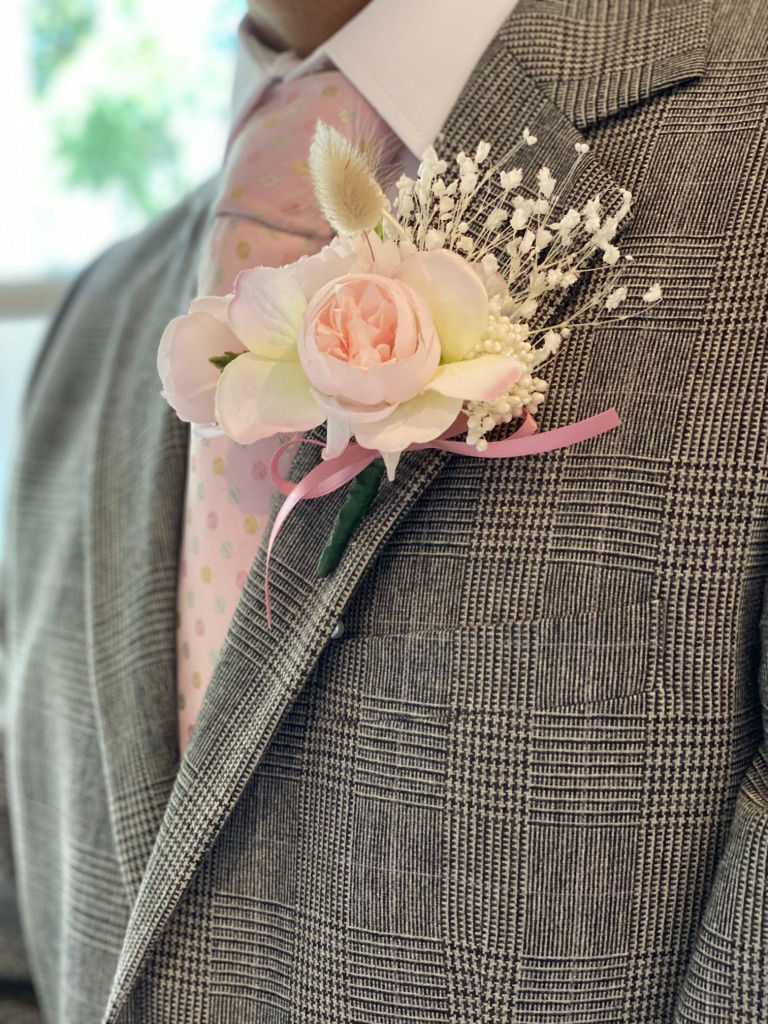 Thumbnail: Man in grey suit with pink tie wearing matching boutonniere with peonies, hydrangea and beige dried bunnytail