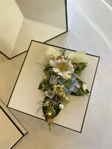 Old Luxe packaging - cream white box with black trim and matching bag. Dress Corsage sitting atop the box with white gerbera daisy and tiny details.