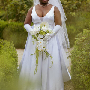 Black Bride in white dress outdoors holding JW Weddings white cascade bouquet with rose, orchid, calla lily
