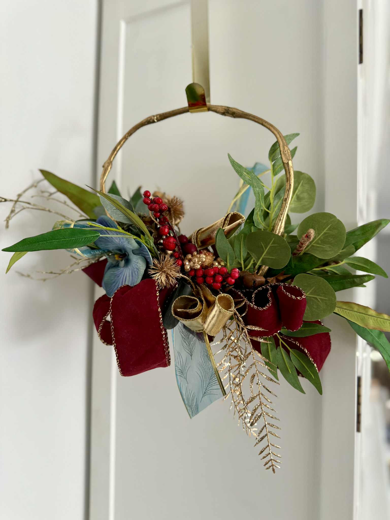 Luxury Australian Christmas wreath with eucalyptus leaves, red berries, gold accents, velvet ribbon, festive front door decor