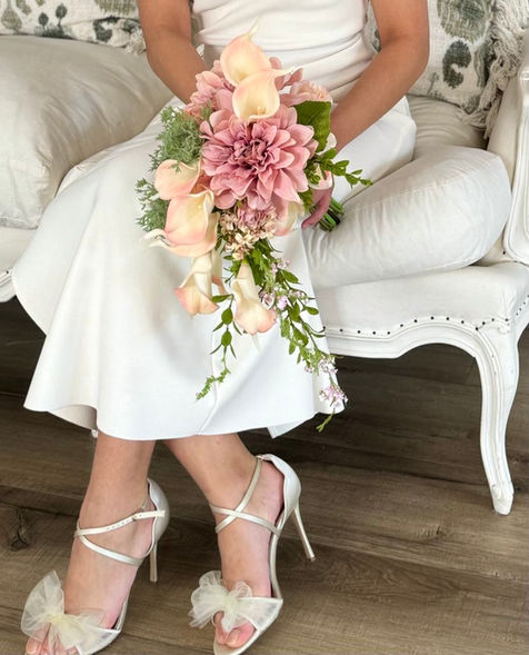 Wedding By Joy Wreaths presents this demure and soft Bouquet- a splendid handmade arrangement in a Bridgerton-style. 
Stunning luxe, this handmade bouquet features quality Artificial Real touch & Silk quality florals - calla lily and dahlia in the most sumptuous soft pink hues and real-touch.  These flowers are so lifelike, you will be a faux flower convert! 
A sight to behold, this beautiful bouquet can be coordinated to match with your maid of honour and bridesmaids, Bride and also the groomsmen. 
We can't decide what is the hero of this bouquet - the colour scheme or arrangement!  A standout dusty pink dahlia is surrounded by gorgeous ivory/pink-tinged calla lilies surrounded by greenery and trailing foliage with small pink buds.
Enquire about having your very own dream bouquet right here with us, one that does not wilt and that you can keep as a momento of your Wedding Day for many years to come. Real touch artificial florals do not compare to real flowers.  They withstand weather, are allergy-friendly, do not leech colour onto your clothing, and look vibrant in photographs.