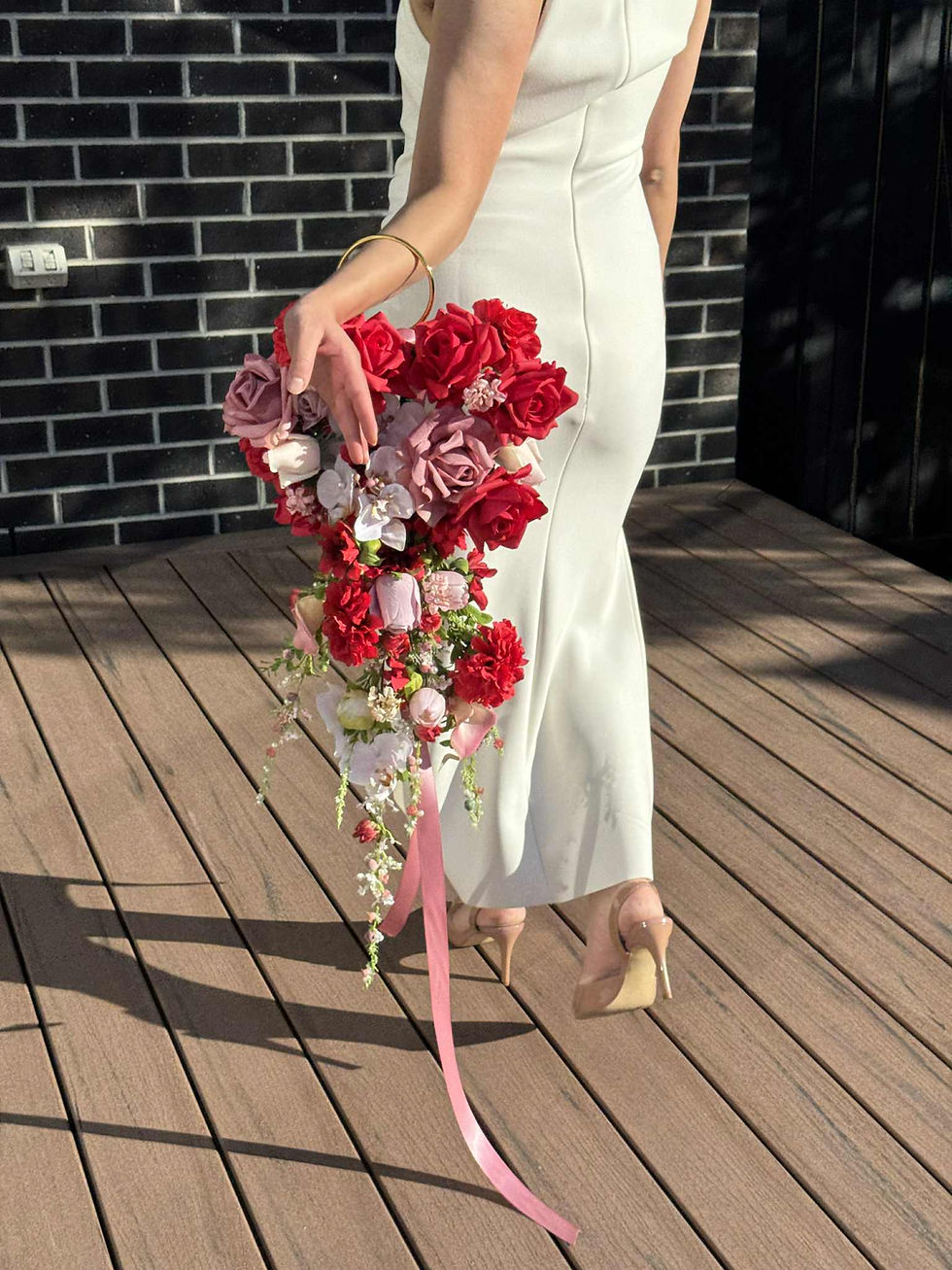 Thumbnail: Bride holding a gold hoop cascading bridal bouquet with red roses, mauve roses, pink orchids, and trailing ribbons – luxury a