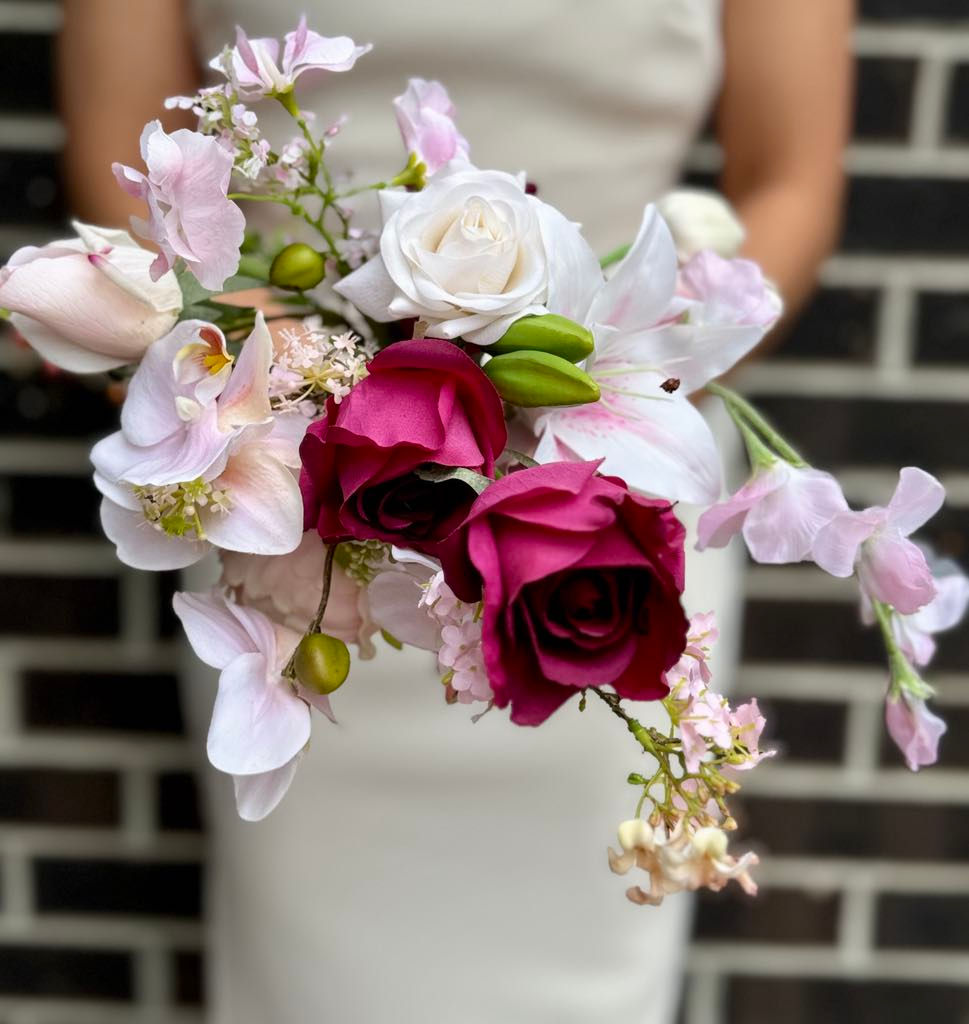 Thumbnail: Side view of free form maroon wedding bouquet with unstructured shape featuring orchid, rose, tulip, lily of valley