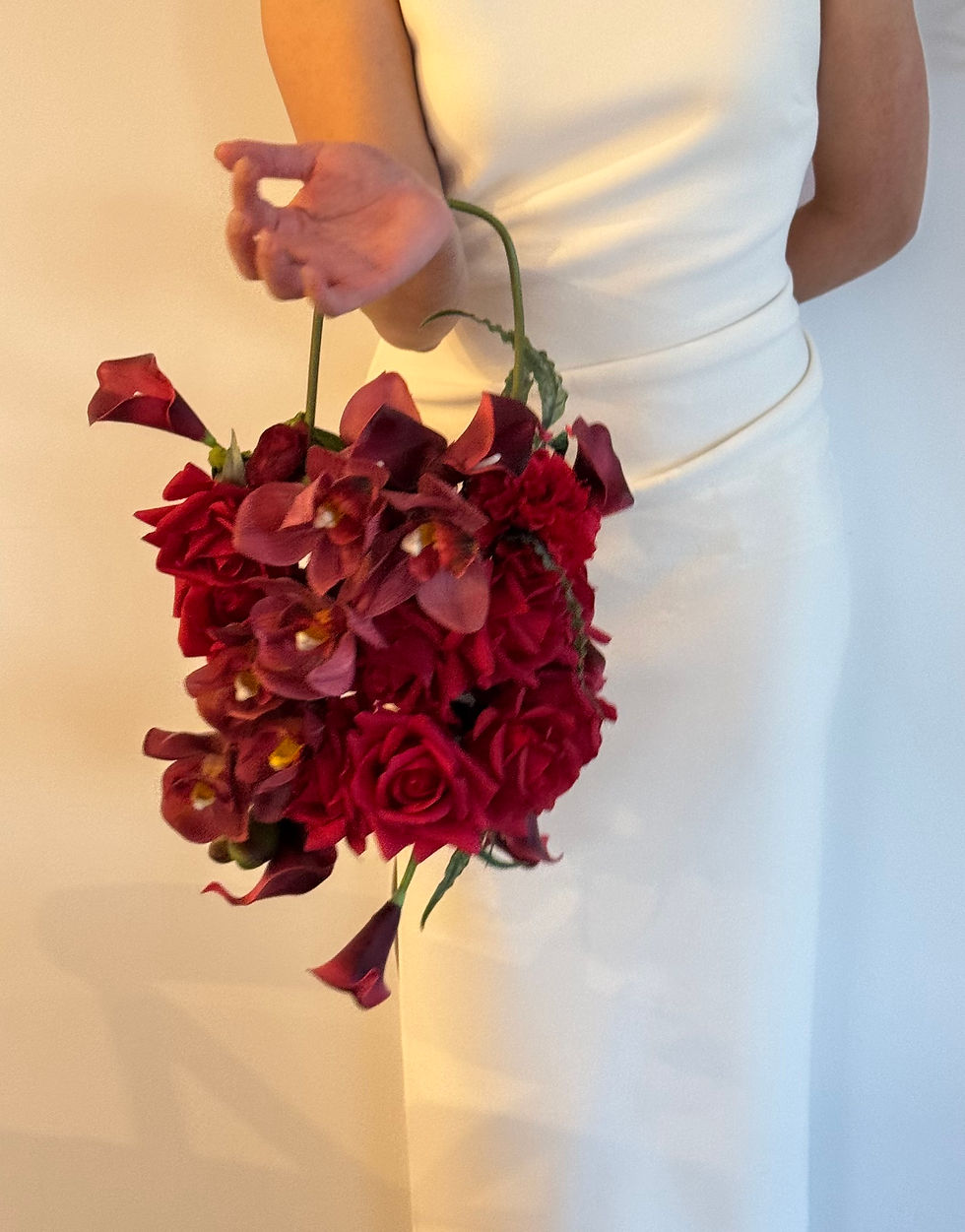 Thumbnail: Bride in white holding trending purse hoop bouquet made with red roses, calla lily and orchid.