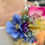 Thumbnail: Close shot of neck shoulder - female wearing white dress with handmade dress corsage pinned with vibrant daisy, calla lily