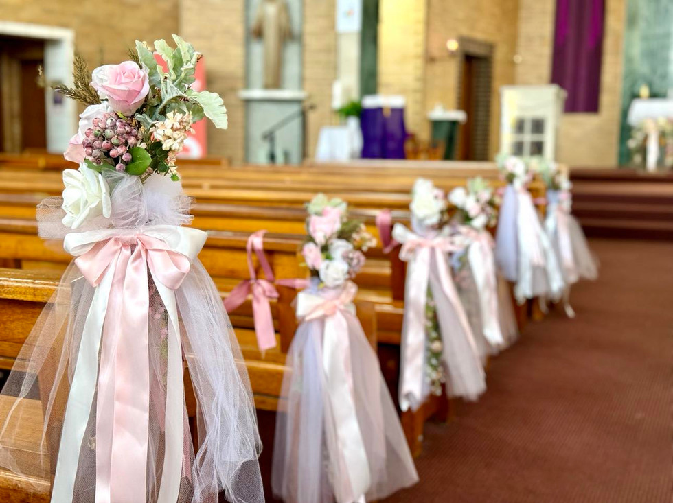 a row of Elegant and timeless faux floral English Rose Garden posies with soft tulle for the brown wood church pews.