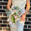 Thumbnail: Woman in white dress holding wedding bouquet in reindeer asymmetrical style