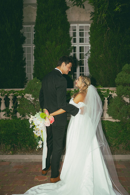 Bride in white strapless dress holding white and pink orchid cascade wedding bouquet