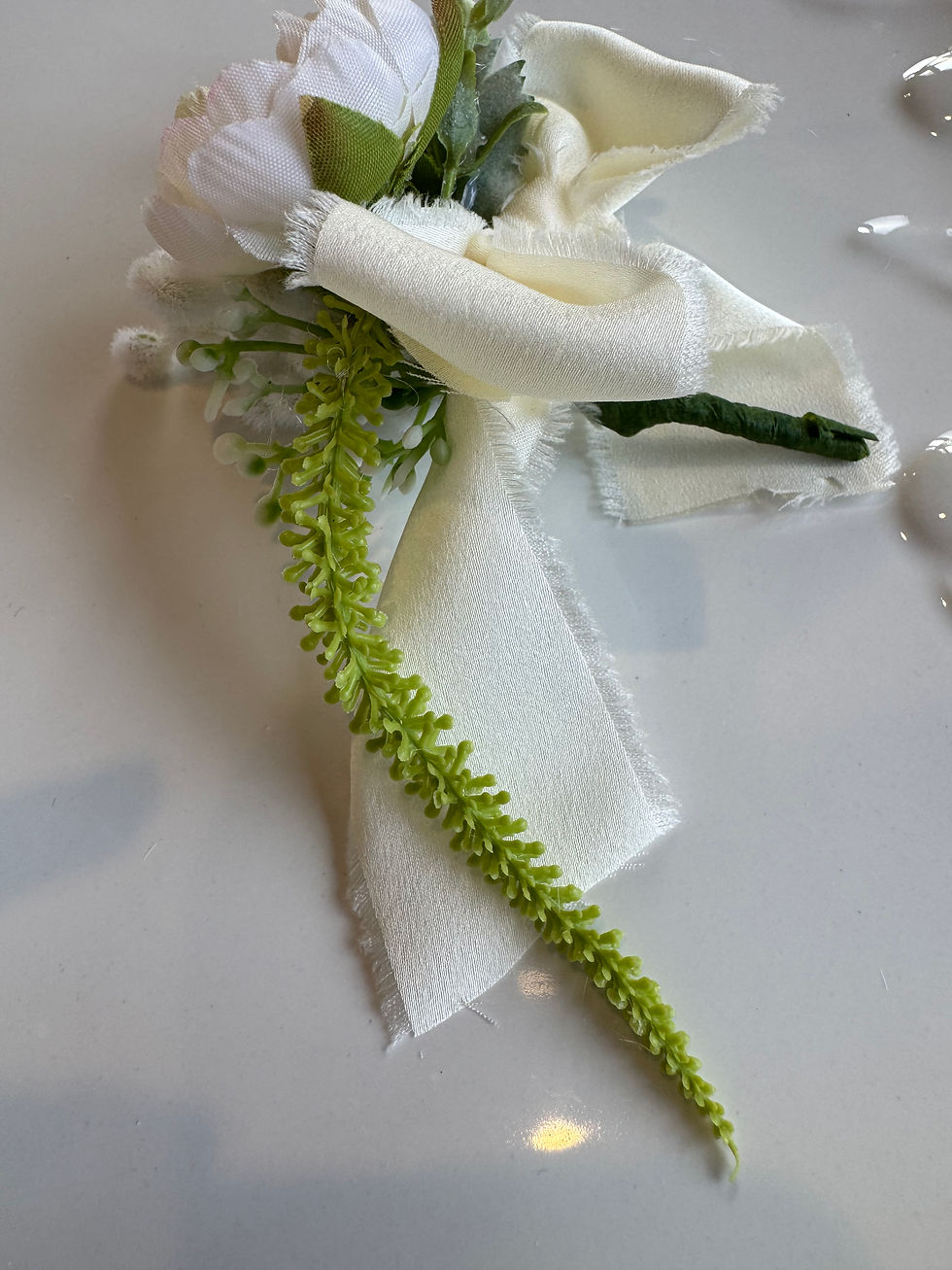 Thumbnail: Close up of JW Weddings artificial buttonhole with off-white peony, green amaranth, desert flame and grand silky bow