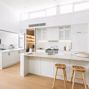a kitchen with white cabinets and wooden stools