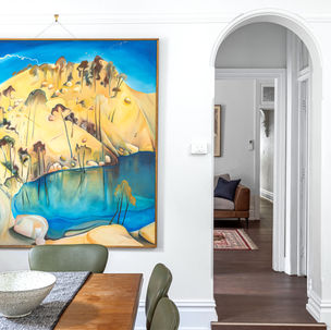 a large painting hangs above a dining table and chairs