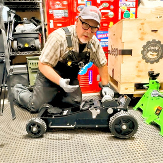 Muddy Ruttzz Bought A Jack and is kneeling down on the garage floor with a Mopar Parts Crate and 2 neon green jack stands. All items were purchased to upgrade a Jeep Gladiator.