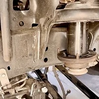 Stock coil spring isolator to be removed to DIY install Mopar Bilstein Jeep lift kit.