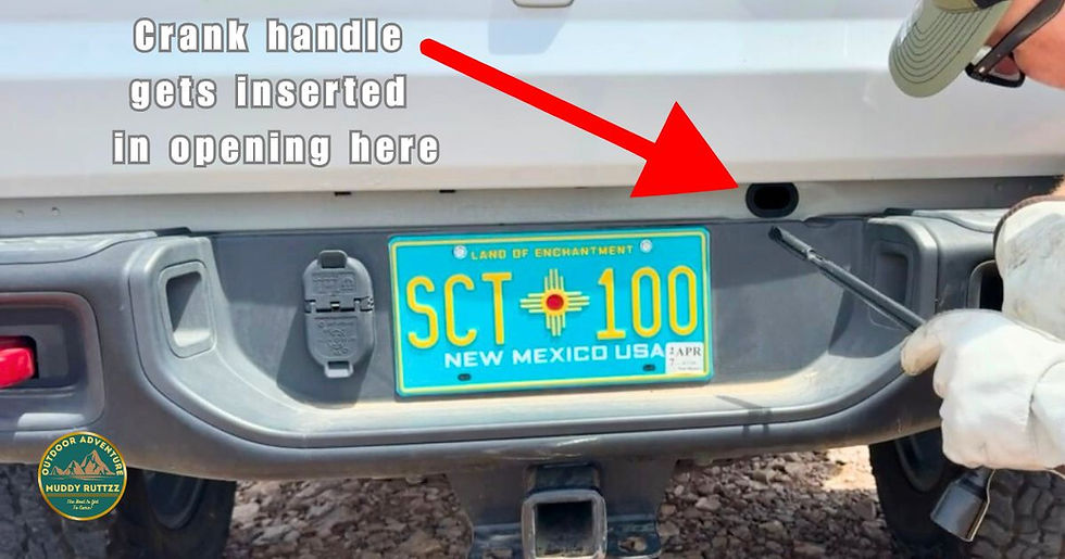Person in gloves holds crank handle near vehicle bumper with New Mexico plate. Text and arrow indicate insertion point on the bumper.