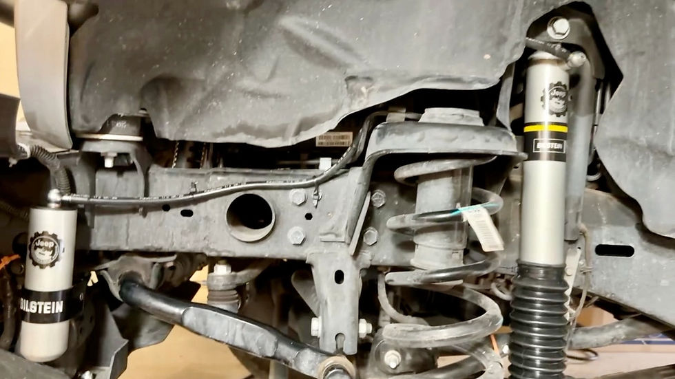 Close-up of a vehicle suspension system featuring Bilstein shocks and springs. Dusty metal components fill the image, suggesting a workshop setting.
