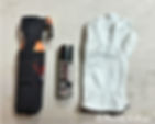 Bear Spray, pepper Spray and a pair of gloves sitting on a table.