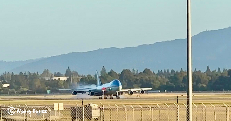 Air Force One the presidential 747 touching down at Moffett Field. Smoke visible from tires contacting tarmac and front wheel still in air.