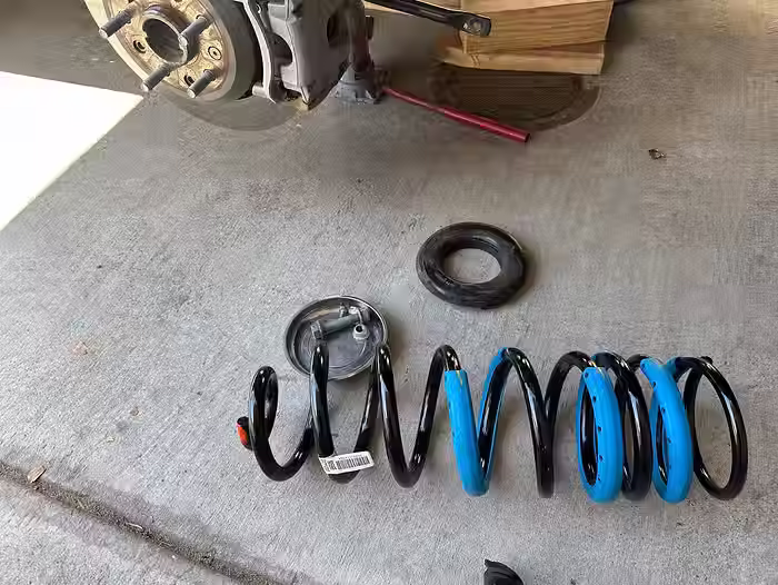 New rear coil spring laying on the ground in preparation for installation on Jeep Gladiator Rubicon.