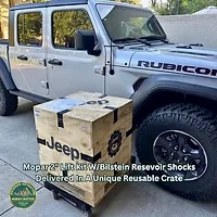 Jeep parts crate containing Mopar Bilstein lift kit next to Jeep Gladiator it will be installed on parked in driveway text on screen and logo visible.