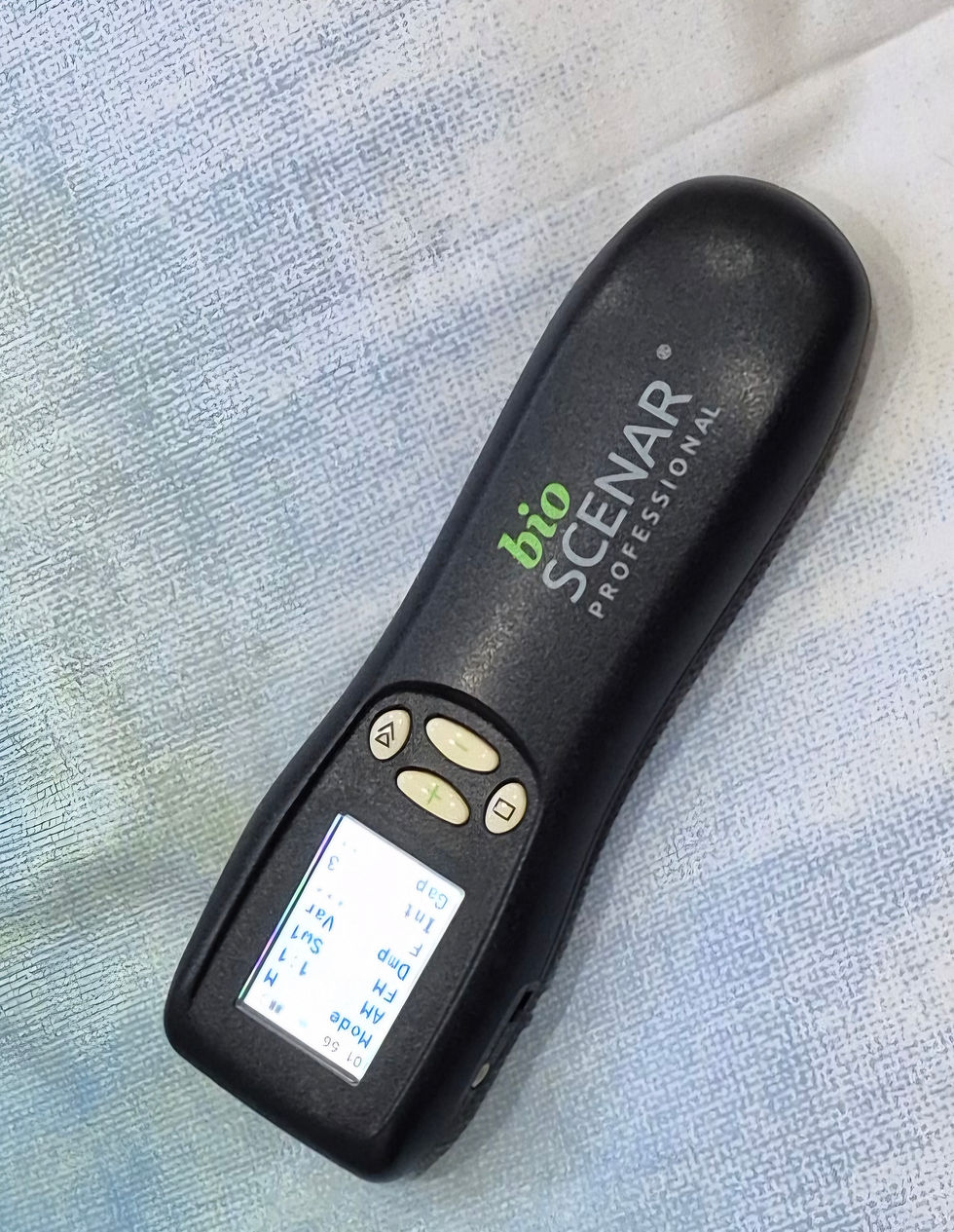 Sideways photo of a handheld bio SCENAR professional device on a textured fabric background, portrait orientation.