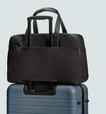 Black Away Everywhere Bag sitting on top of a blue suitcase